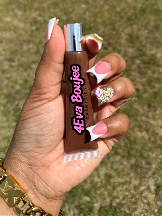 Hand holding a small bottle labeled '4eva Boujee' against a grassy background