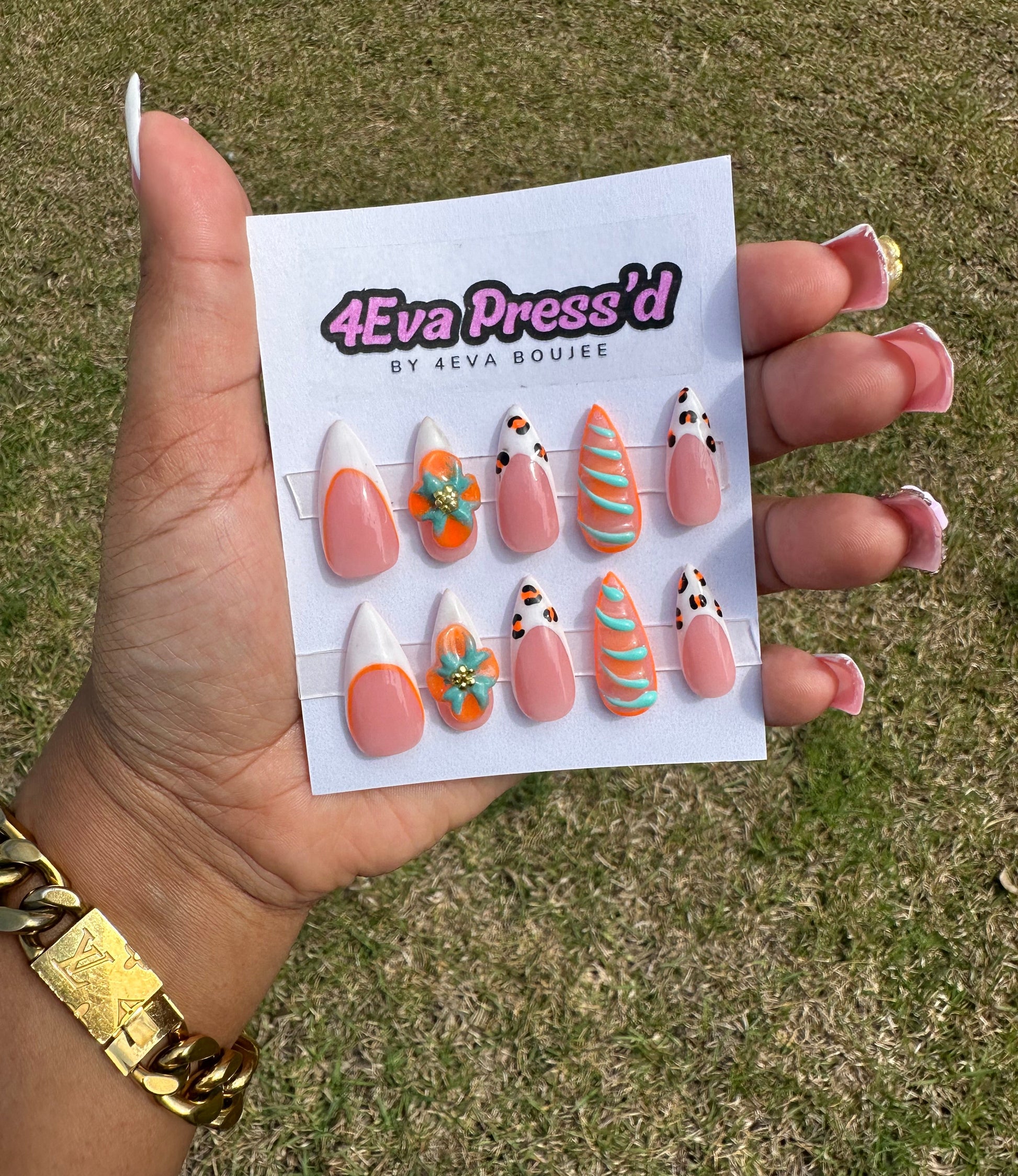 Hand holding a card with nail art designs against a grassy background
